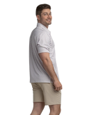Man wearing a transfusion patterned Southern Shirt Co polo shirt and beige shorts on a white background
