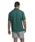 Man wearing a Green polo shirt with deer antler pattern and light gray shorts on a white background