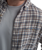 Plaid shirt over a gray t-shirt with a visible brand logo on a white background