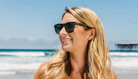 Woman wearing sunglasses with a beach background