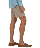 Person wearing beige shorts with a white background