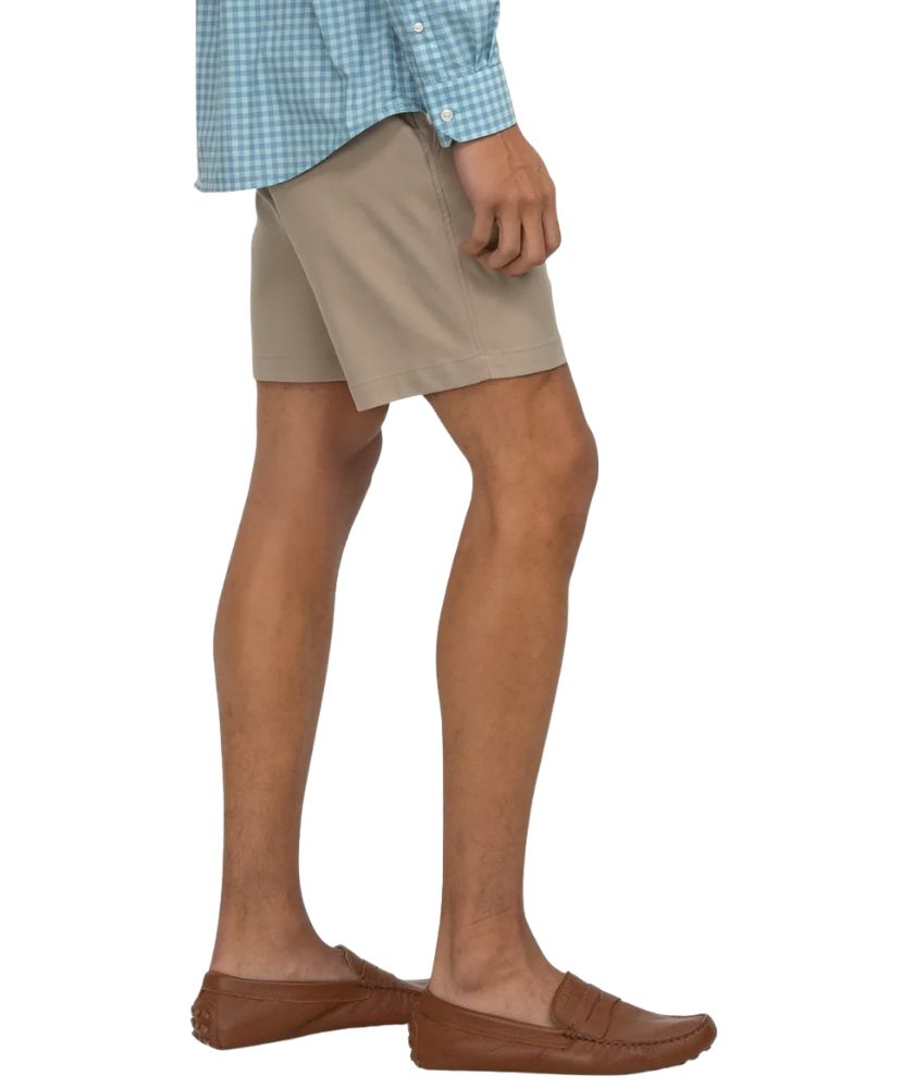 Person wearing beige shorts with a white background
