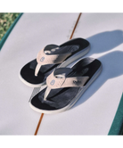 Pair of black and rose gold sandals on a light surface with grass in the background