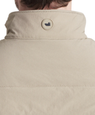 Close-up of a beige jacket with a brand logo on the collar against a white background