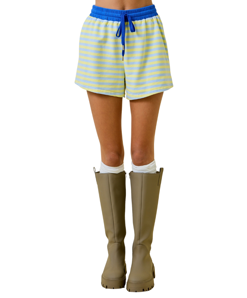Person wearing yellow and blue striped shorts with beige rubber boots on a white background