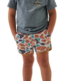 Child wearing a gray t-shirt and camo patterned swim shorts on a white background