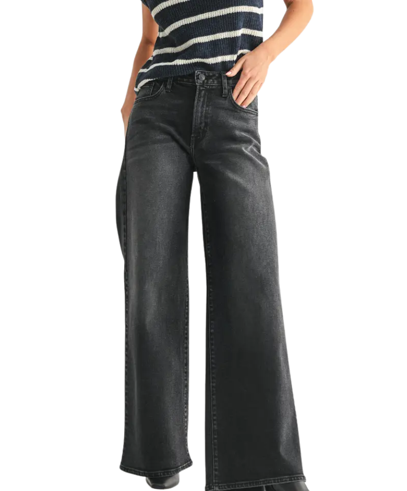 Person wearing black wide-leg jeans and a striped shirt on a white background
