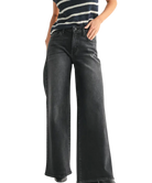 Person wearing black wide-leg jeans and a striped shirt on a white background