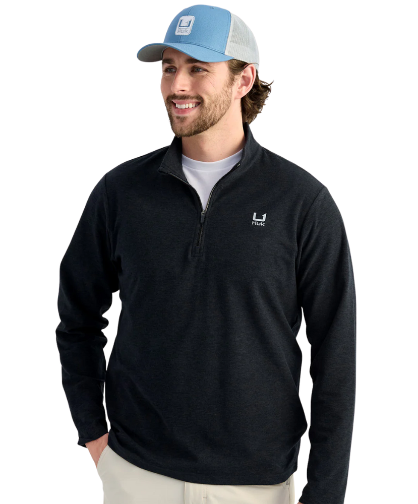 Man wearing a black quarter-zip pullover with a HUK ogo on a white background