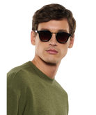 Man wearing Krewe sunglasses and a green sweater on a white background
