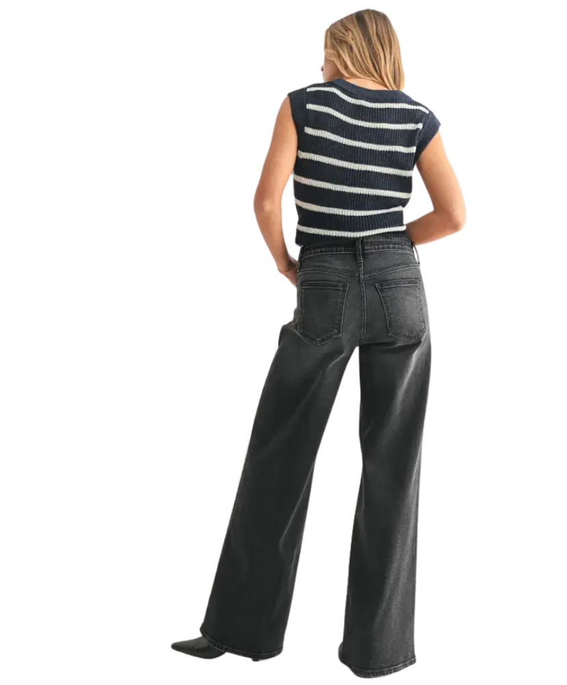 Person wearing a striped shirt and black jeans on a white background