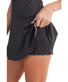 Woman wearing a black polka dot dress with built-in pockets on a white background