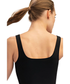 Woman wearing a black tank top with a plain white background