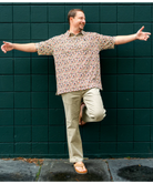 Man with arms outstretched against a green tiled wall
