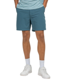 Person wearing teal shorts and white sneakers on a white background