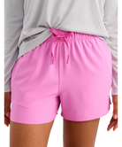 Pink HUK shorts worn by a person with a gray long-sleeve shirt.