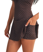 Woman wearing a brown polka dot dress WITH POCKETS on a white background