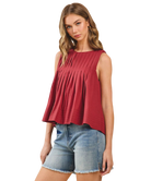 Woman wearing a burgundy sleeveless top and denim shorts on a white background