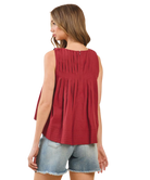 Woman wearing a burgundy sleeveless top and denim shorts on a white background