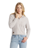 Woman wearing a light gray patterned sweater and blue jeans on a white background