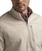 Tan quarter zip pullover with a plaid shirt underneath on a white background