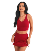 Woman wearing a red sports bra and skirt set on a white background