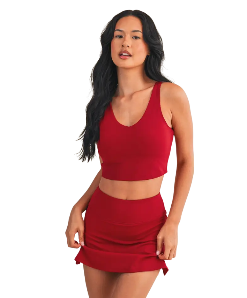 Woman wearing a red sports bra and skirt set on a white background