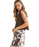 Woman wearing a brown sleeveless sweater over a floral dress on a white background