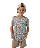 Child wearing a camouflage t-shirt and beige shorts on a white background