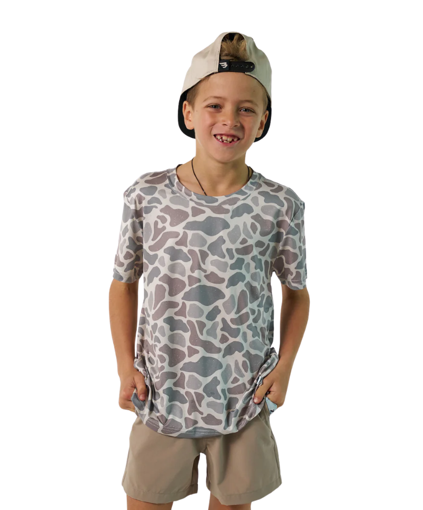 Child wearing a camouflage t-shirt and beige shorts on a white background