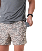 Person wearing camouflage shorts and a gray shirt on a white background