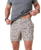 Person wearing camouflage shorts and a gray t-shirt on a white background
