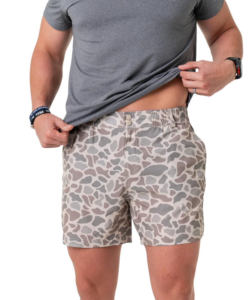 Person wearing camouflage shorts and a gray t-shirt on a white background