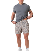 Man wearing a gray t-shirt and camoflage patterned shorts on a white background
