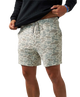 A person wearing patterned shorts and pulling up a black long-sleeve shirt against a plain white background.