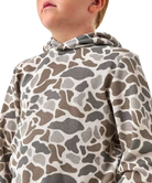 A close-up of a child wearing a waffle-knit hooded sweatshirt with an abstract organic animal-style print in brown, gray, and beige tones against a plain white background.