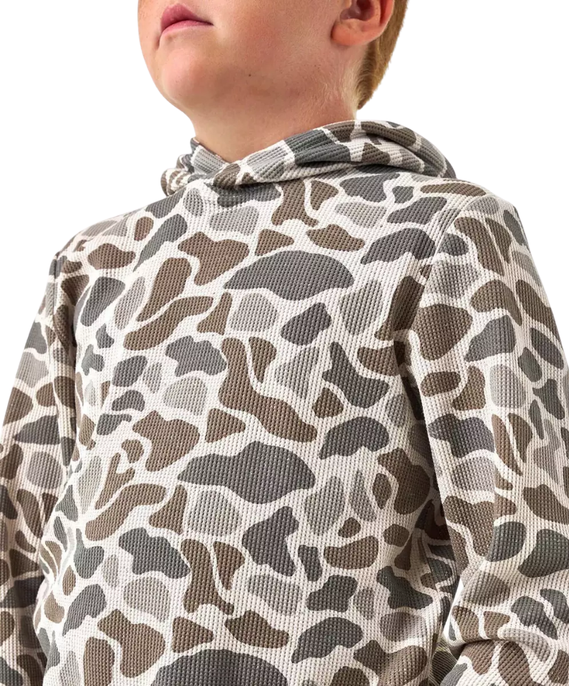 A close-up of a child wearing a waffle-knit hooded sweatshirt with an abstract organic animal-style print in brown, gray, and beige tones against a plain white background.
