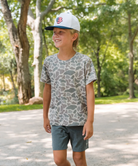 Child wearing a cap and camo patterned t-shirt in a park setting