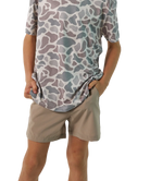 child wearing a camo patterned t-shirt and beige shorts on a white background