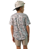 Child wearing a camo patterned t-shirt and cap on a white background