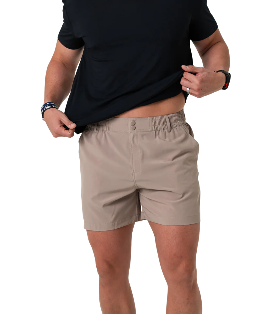 Person wearing beige shorts and a black shirt on a white background