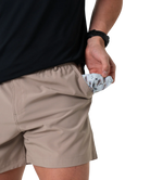 Person wearing beige shorts with a black shirt, holding a patterned handkerchief.