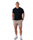 Man wearing a black t-shirt, beige shorts, and a cap on a white background