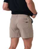 Beige shorts worn by a person on a white background