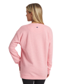 Person wearing a pink long-sleeve shirt with a brand logo on the back against a white background