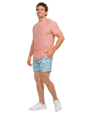 Man wearing a Pink short-sleeve henley shirt and patterned shorts on a white background