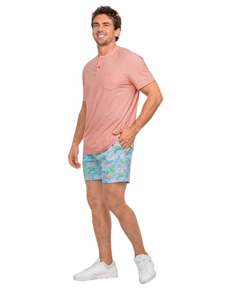Man wearing a Pink short-sleeve henley shirt and patterned shorts on a white background