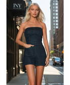 Woman in a dark denim romper walking on a city street.