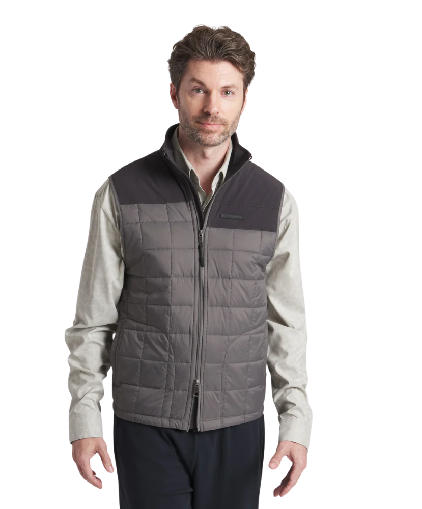 Man wearing a gray quilted vest over a light shirt on a white background