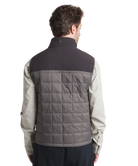 Man wearing a two-tone jacket with a quilted gray back on a white background